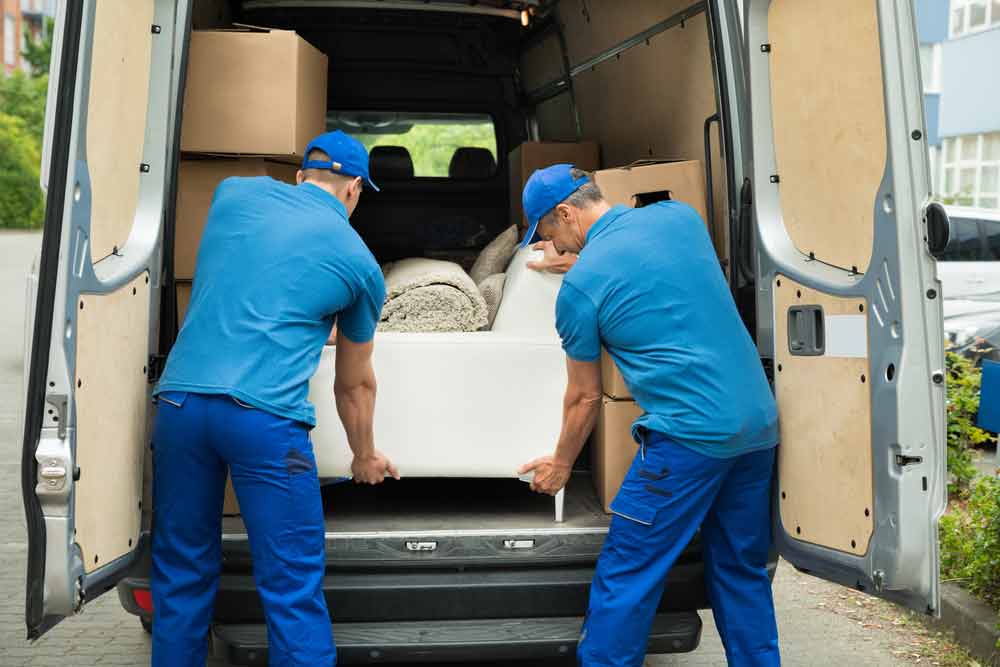 Two Man Unloading A White Sofa Off The Van