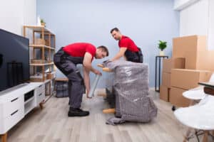Removalists Wrapping A Sofa Carefully